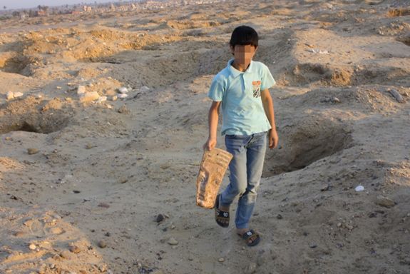 Ребенок среди колодцев, вырытых грабителями для доступа к захоронениям в Египте