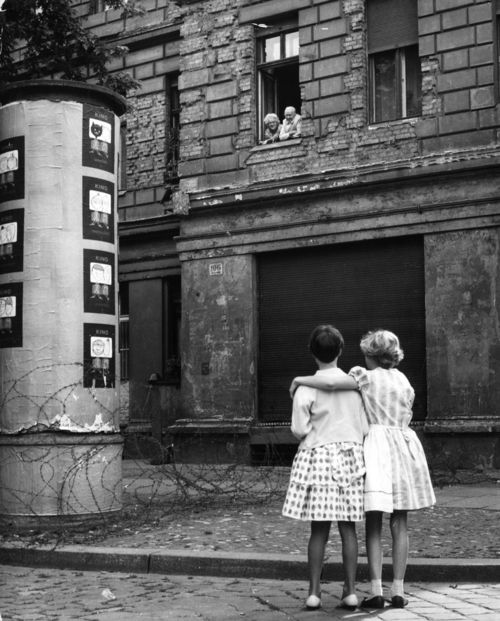 Девушки из Западной Германии разговаривают с дедом и бабкой из Восточной, рядом с первым вариантом Берлинской стены